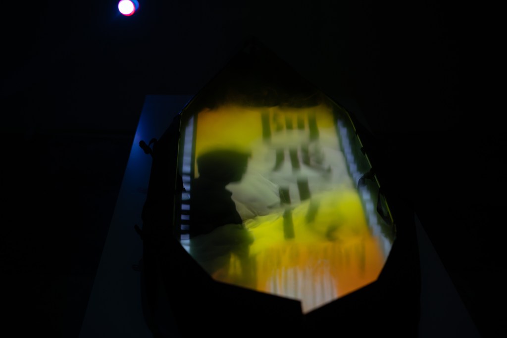 鄭靖《流動的愉悅III： 陸上行舟》，船的造型是回應油街實現曾經是遊艇會會所。燈光投射的影像內藏藝術家挑選的十部電影，向香港電影致敬。